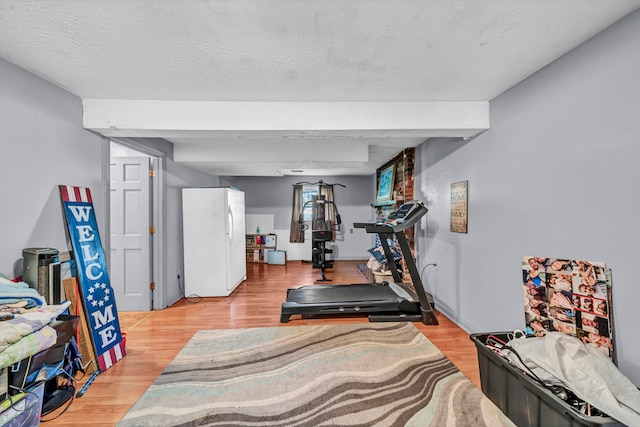 workout room with light hardwood / wood-style flooring and a textured ceiling