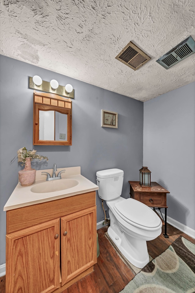 bathroom with vanity, toilet, hardwood / wood-style flooring, and a textured ceiling