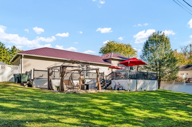 rear view of property featuring a wooden deck and a lawn