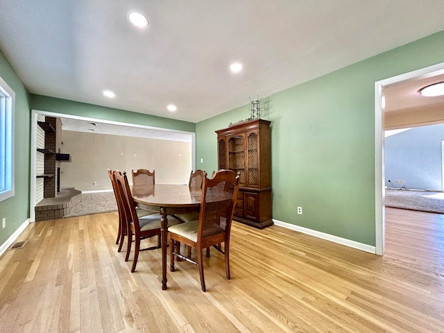 dining room with light hardwood / wood-style flooring and a fireplace