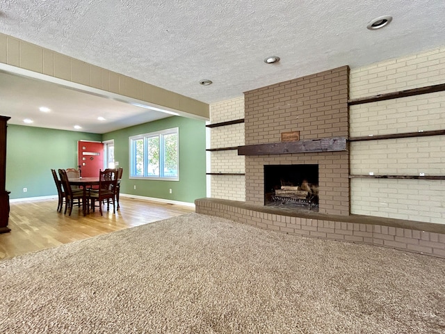 living room featuring light hardwood / wood-style floors, a textured ceiling, and a fireplace