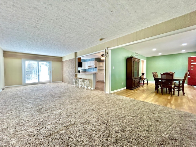 living room with light hardwood / wood-style floors, a textured ceiling, and ceiling fan