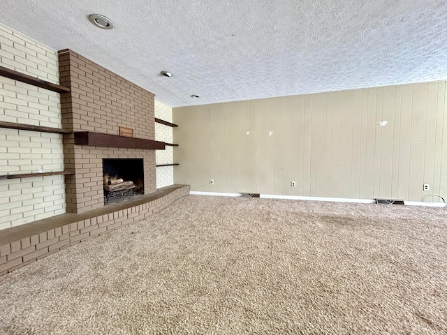 unfurnished living room with a textured ceiling, a fireplace, carpet flooring, and wooden walls