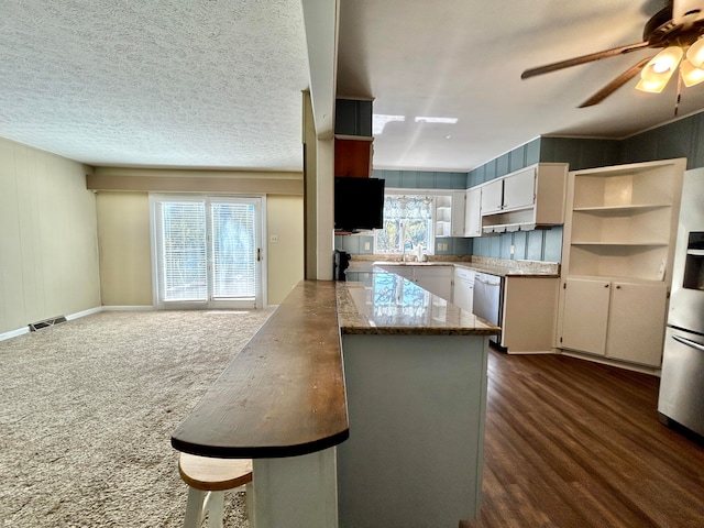 kitchen featuring a textured ceiling, white cabinetry, dark hardwood / wood-style floors, and a healthy amount of sunlight