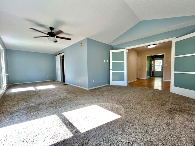 carpeted empty room with ceiling fan, lofted ceiling, and a barn door