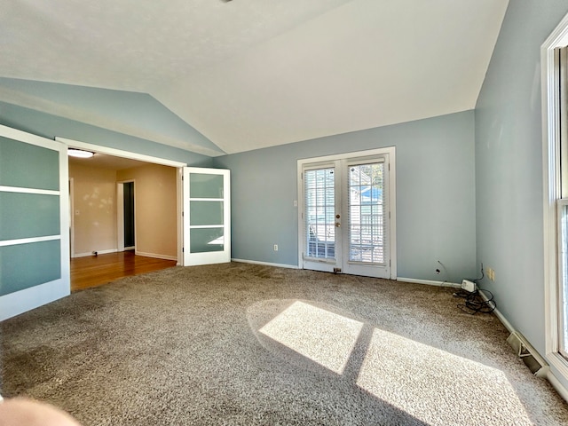 spare room featuring french doors, carpet, and vaulted ceiling