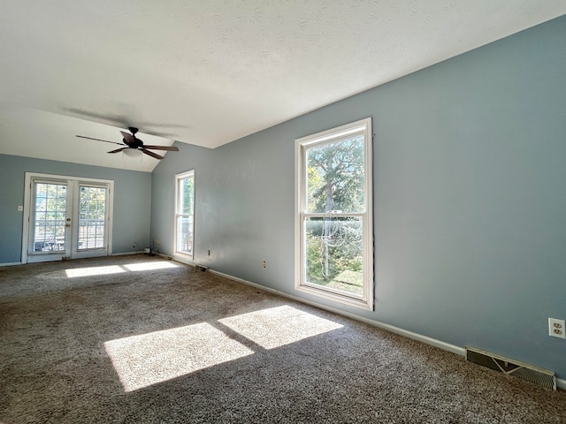 empty room featuring ceiling fan, a textured ceiling, carpet flooring, vaulted ceiling, and french doors