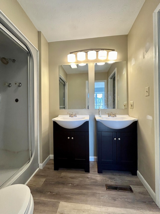 bathroom featuring vanity, toilet, wood-type flooring, and a textured ceiling