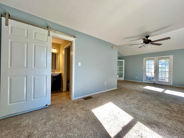 carpeted spare room featuring french doors, ceiling fan, vaulted ceiling, and a barn door