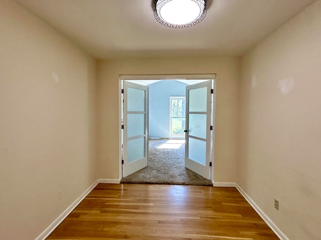 corridor with french doors and hardwood / wood-style floors