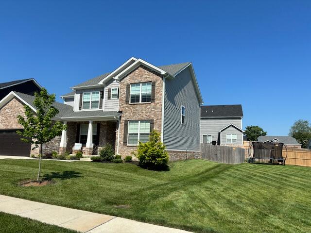 craftsman-style house with a front yard and a trampoline