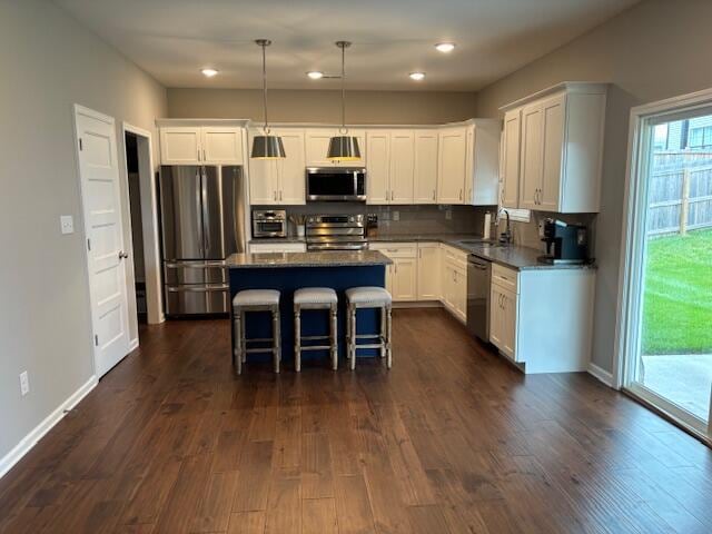 kitchen featuring hanging light fixtures, appliances with stainless steel finishes, a kitchen breakfast bar, dark hardwood / wood-style floors, and a center island