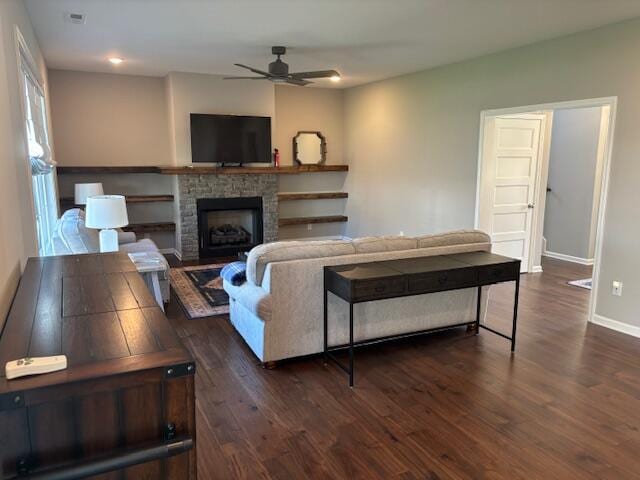 living room featuring ceiling fan, a fireplace, and dark hardwood / wood-style flooring