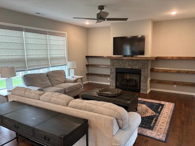 living room with dark wood-type flooring, a fireplace, and ceiling fan