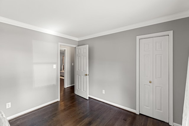 unfurnished bedroom featuring a closet, ornamental molding, and dark hardwood / wood-style flooring