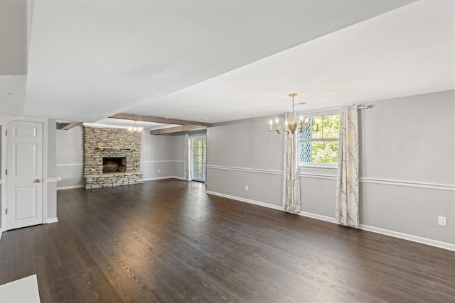 unfurnished living room featuring a notable chandelier, a stone fireplace, and dark hardwood / wood-style flooring