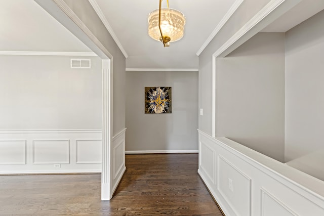 corridor featuring crown molding, an inviting chandelier, and dark hardwood / wood-style floors