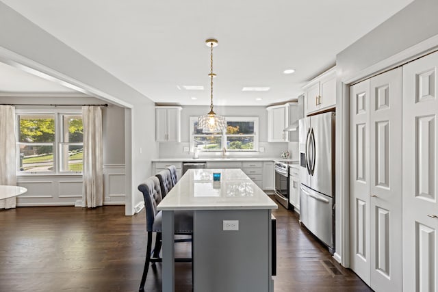 kitchen featuring a center island, white cabinets, a healthy amount of sunlight, and stainless steel appliances