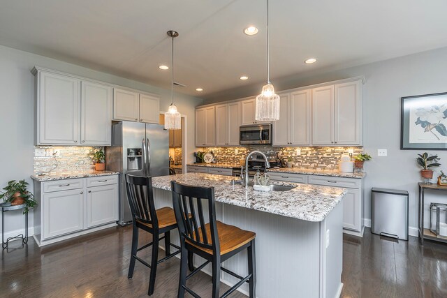 kitchen featuring decorative backsplash, appliances with stainless steel finishes, white cabinetry, dark wood-type flooring, and pendant lighting