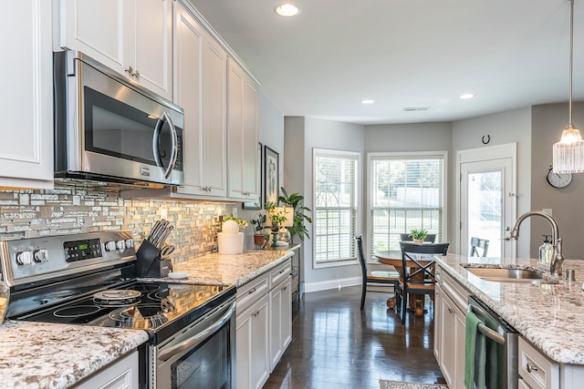 kitchen with decorative light fixtures, white cabinets, stainless steel appliances, and sink