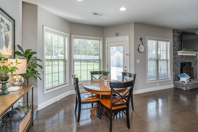 dining room with dark wood-type flooring, plenty of natural light, and a fireplace