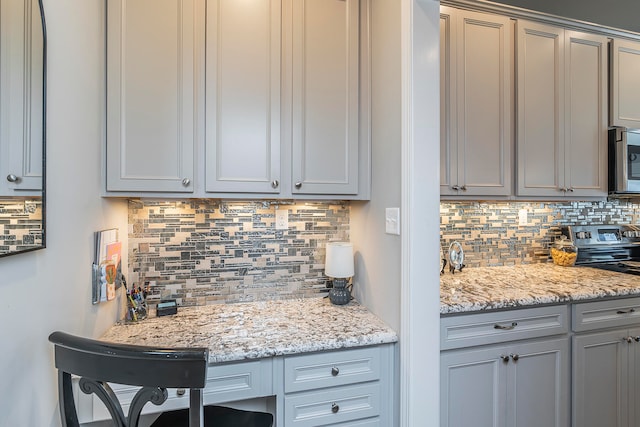 kitchen with gray cabinets, light stone counters, and tasteful backsplash