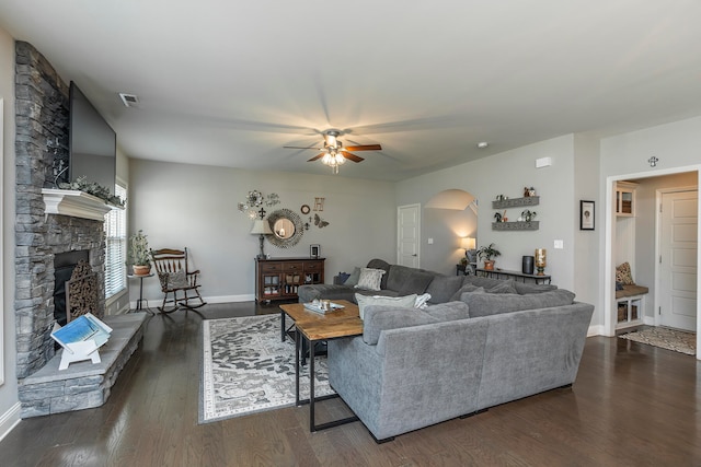 living room with dark wood-type flooring, a fireplace, and ceiling fan