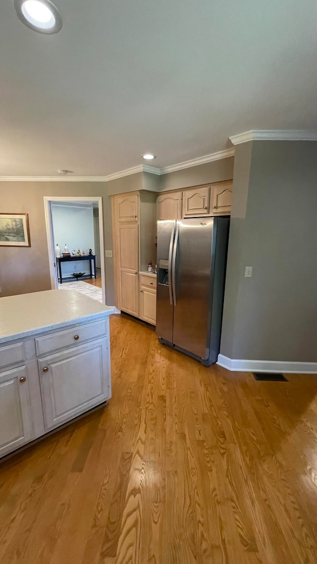 kitchen with stainless steel fridge, light hardwood / wood-style floors, and ornamental molding