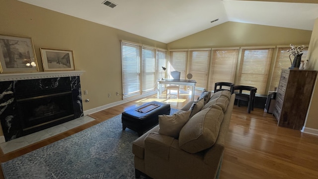 living room featuring light wood-type flooring, lofted ceiling, and a fireplace