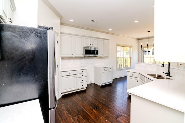 kitchen with hanging light fixtures, white cabinetry, dark hardwood / wood-style floors, sink, and stainless steel appliances