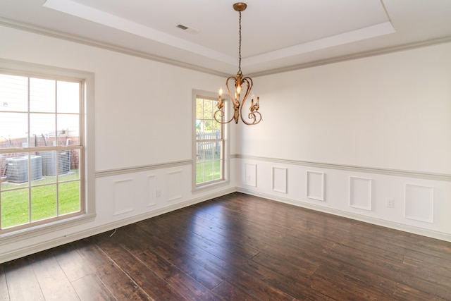 empty room with ornamental molding, a chandelier, dark hardwood / wood-style floors, and a raised ceiling