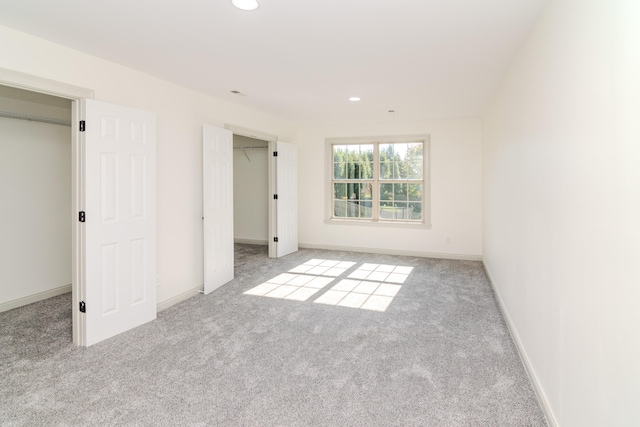 unfurnished bedroom featuring a closet, light carpet, and a walk in closet