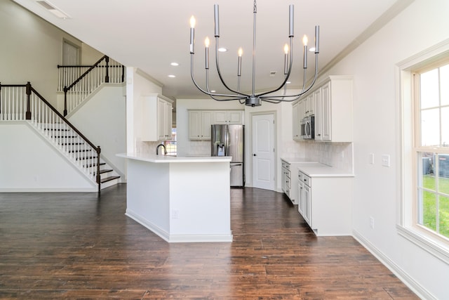 kitchen featuring hanging light fixtures, backsplash, white cabinetry, appliances with stainless steel finishes, and dark hardwood / wood-style flooring