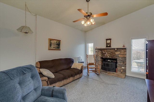 living room with ceiling fan, high vaulted ceiling, and a wood stove