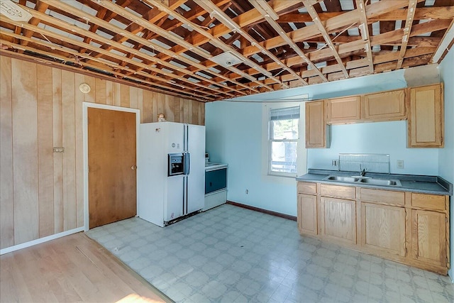 kitchen with white fridge with ice dispenser, sink, range, light brown cabinetry, and wood walls