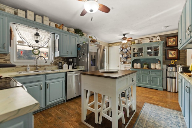 kitchen with appliances with stainless steel finishes, sink, butcher block countertops, ornamental molding, and dark hardwood / wood-style floors