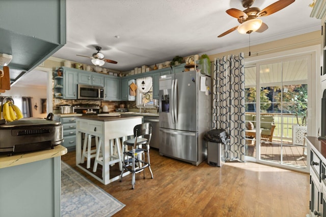 kitchen with stainless steel appliances, ornamental molding, hardwood / wood-style floors, sink, and tasteful backsplash