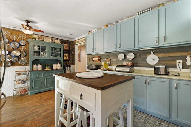 kitchen with blue cabinetry, crown molding, and dark hardwood / wood-style floors