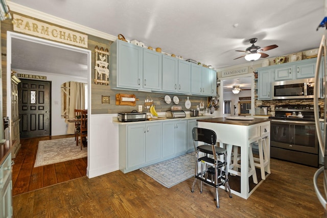 kitchen with backsplash, dark hardwood / wood-style flooring, blue cabinetry, appliances with stainless steel finishes, and ceiling fan