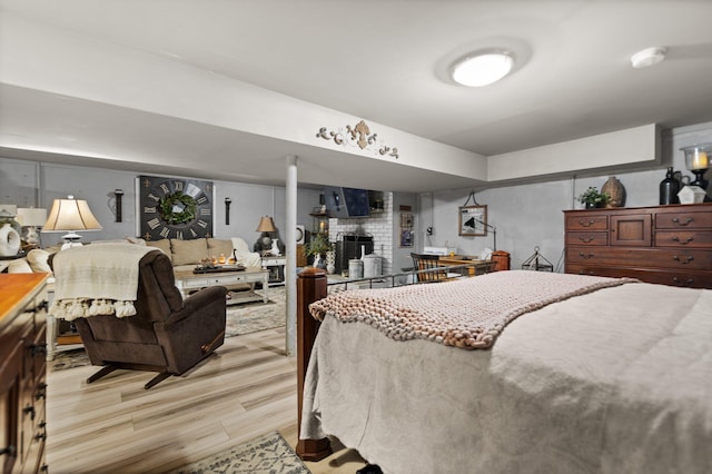 bedroom with a large fireplace and light wood-type flooring