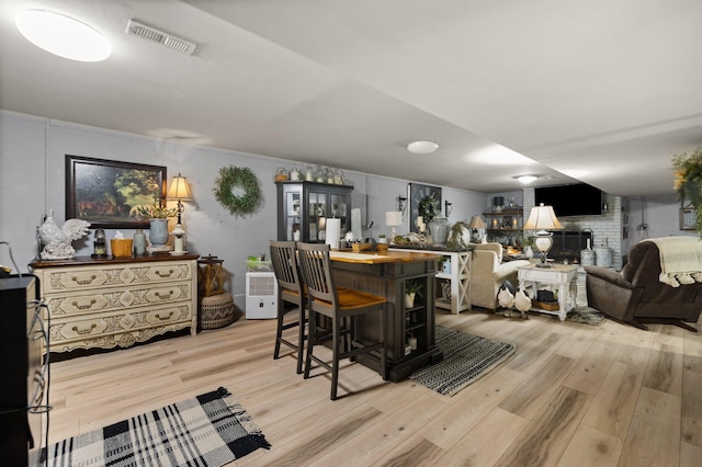 dining area featuring light hardwood / wood-style flooring, bar, and a fireplace