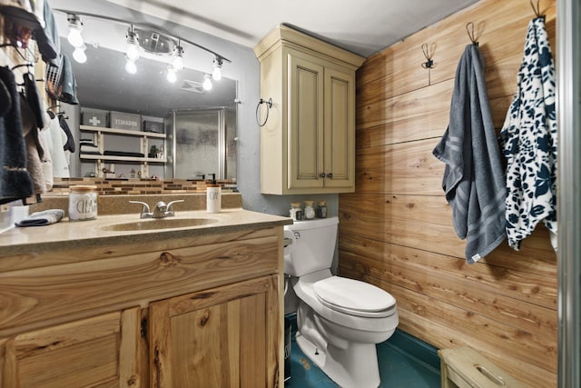 bathroom featuring toilet, wooden walls, and vanity