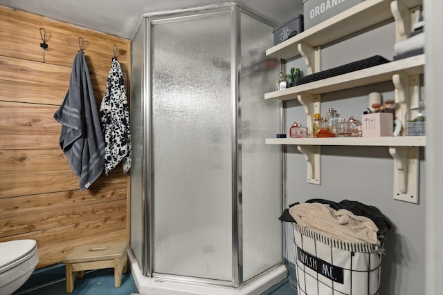 bathroom with a shower with door, toilet, and wood walls