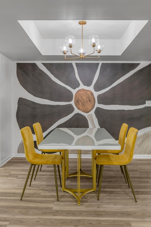 dining room with hardwood / wood-style floors, a chandelier, and a raised ceiling