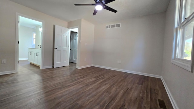 unfurnished bedroom featuring dark wood-type flooring, ceiling fan, connected bathroom, and sink