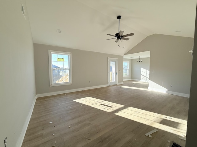 unfurnished living room with hardwood / wood-style floors, a wealth of natural light, and vaulted ceiling