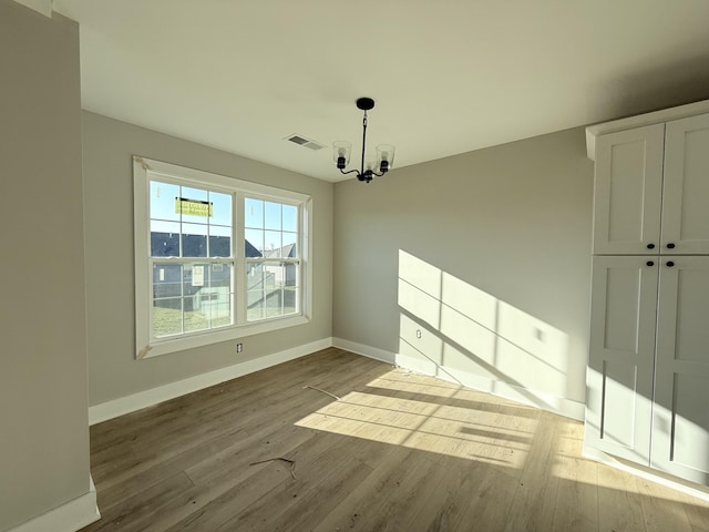 unfurnished dining area featuring light hardwood / wood-style flooring and a notable chandelier