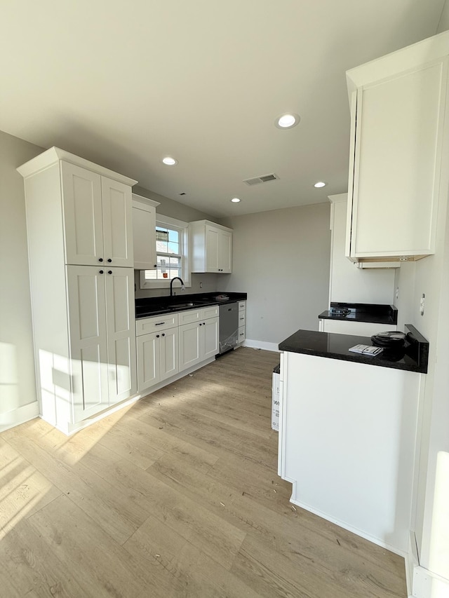 kitchen with white cabinets, light hardwood / wood-style flooring, dishwasher, and sink