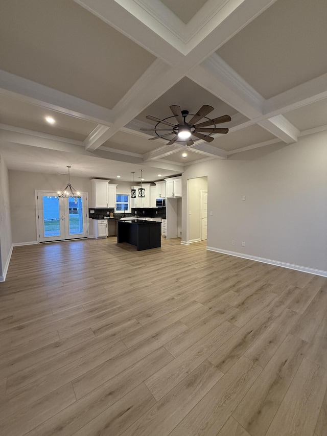 unfurnished living room featuring beam ceiling, ceiling fan, and coffered ceiling