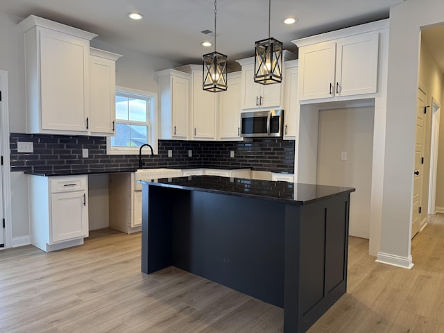 kitchen with white cabinets, a kitchen island, and hanging light fixtures